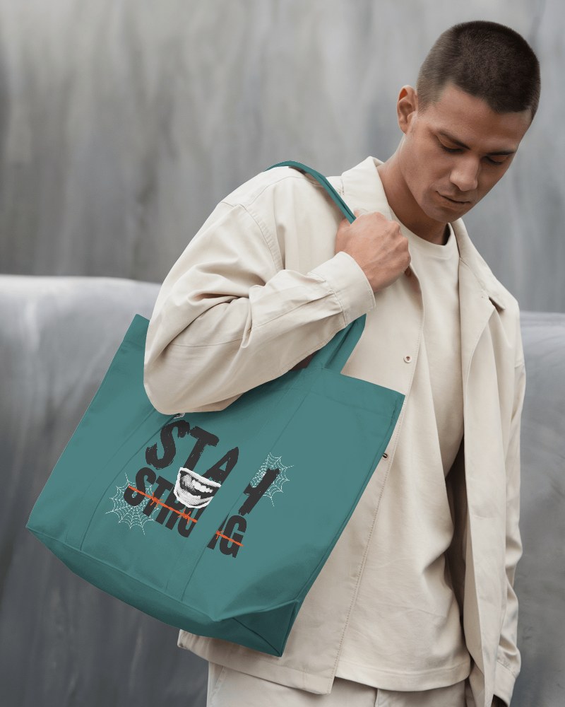 Minimalist Streetwear Tote Bag Mockup Male Model In Monochrome Outfit Looking Down Against Textured Gray Background 0150