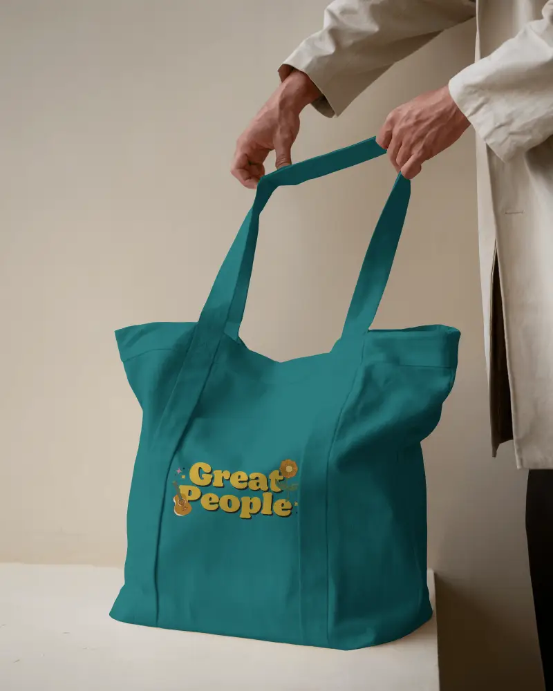 Standing Pose Totebag Mockup Male Model Holding Bag With Both Hands Minimalist Interior Soft Lighting Uplifting Message In Retro Typography Casual And Positive Vibe