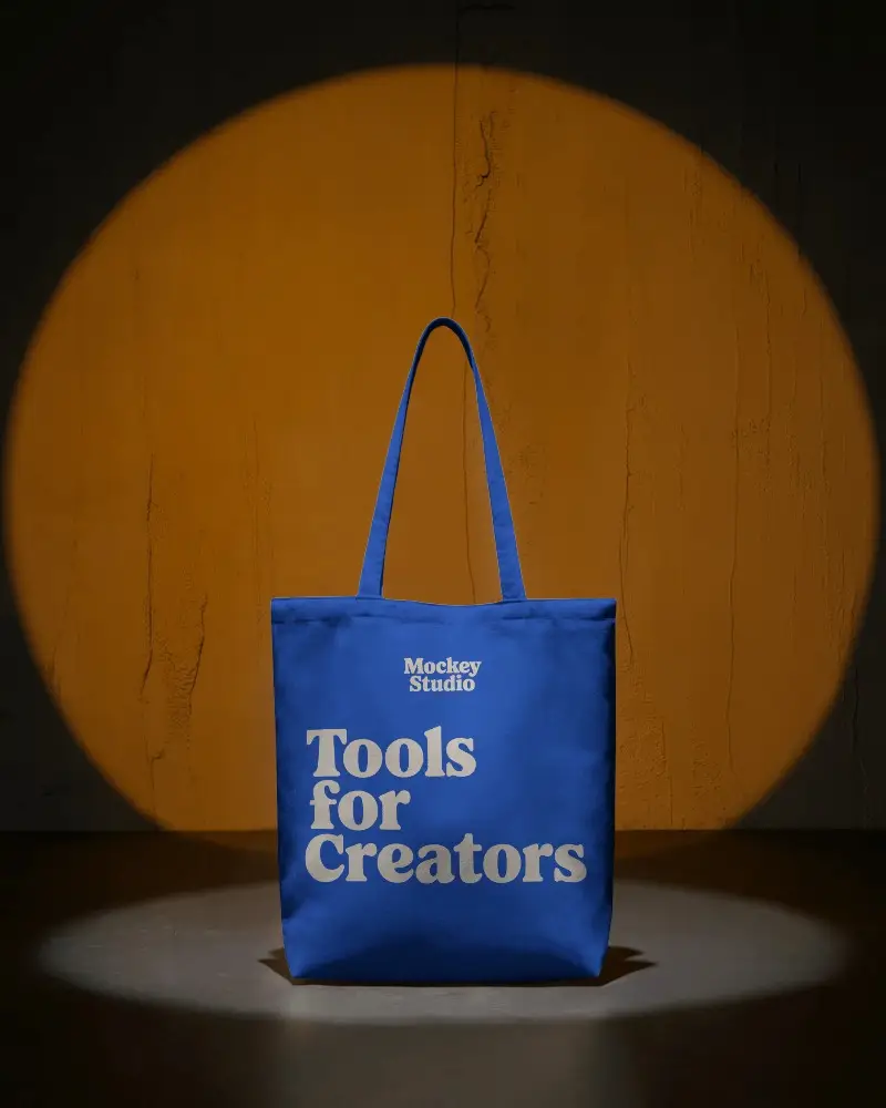 Spotlight Tote Bag Mockup Against Textured Orange Wall In Dark Studio