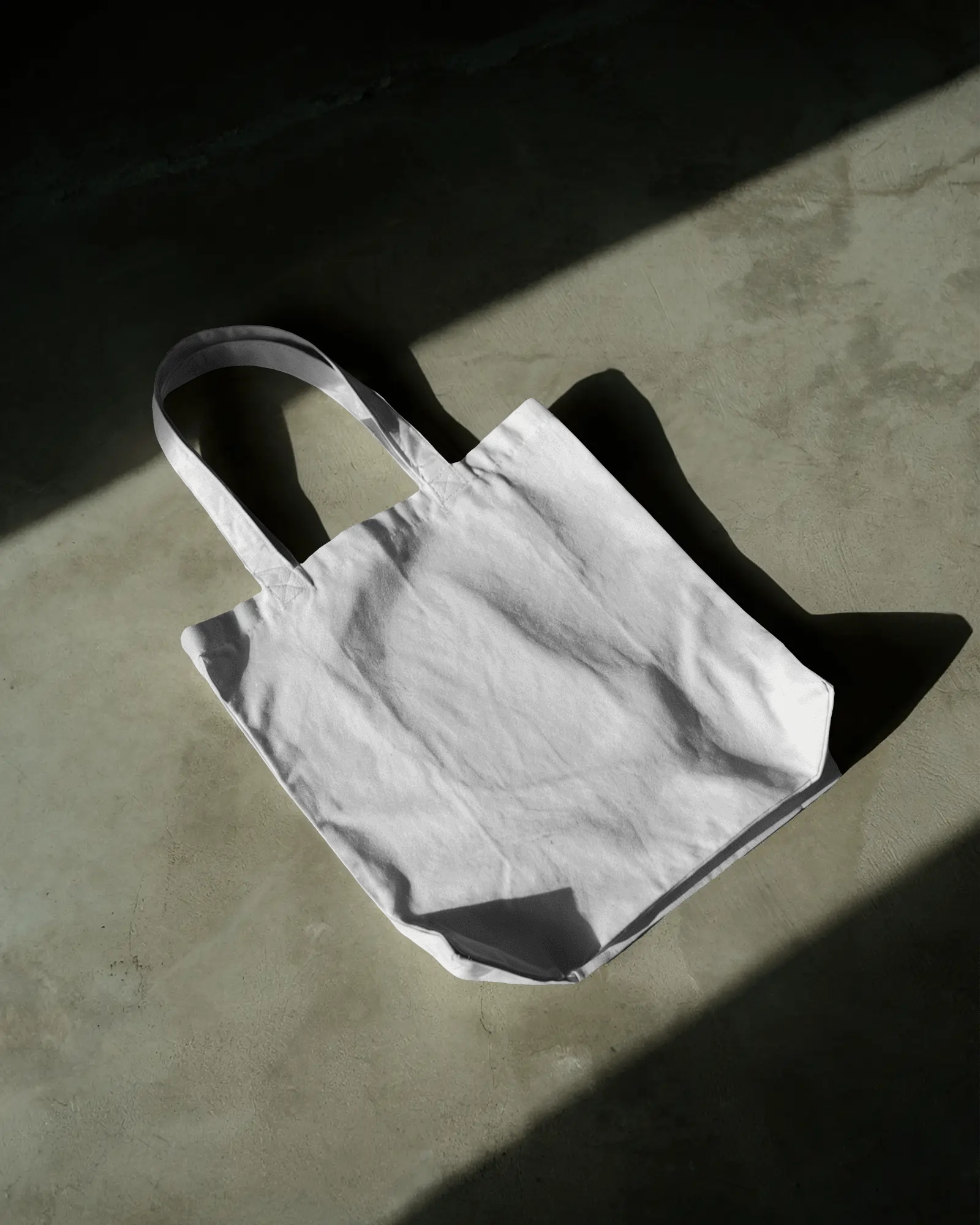 minimalist-tote-bag-mockup-on-concrete-floor-with-dramatic-lighting-modern-eco-lifestyle-design