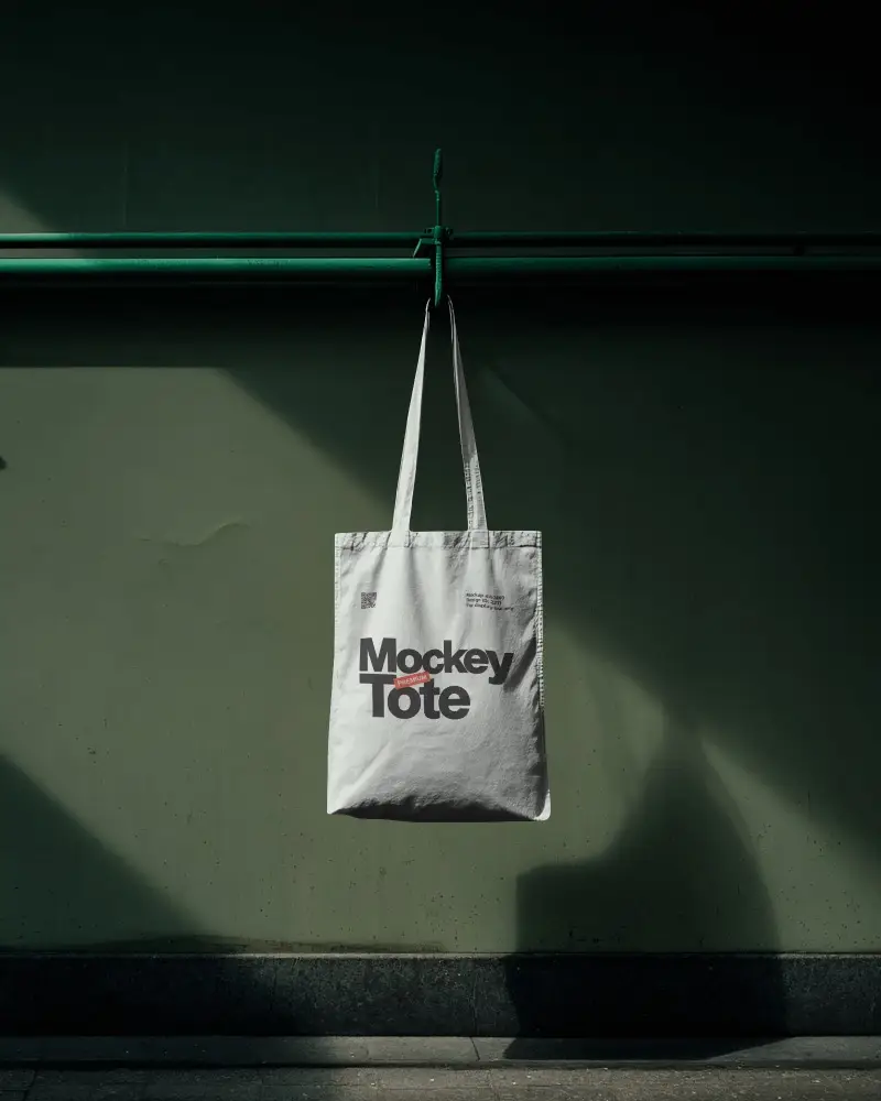 Hanging Wall Totebag Mockup With Minimal Industrial Backdrop And Dramatic Shadow Lighting