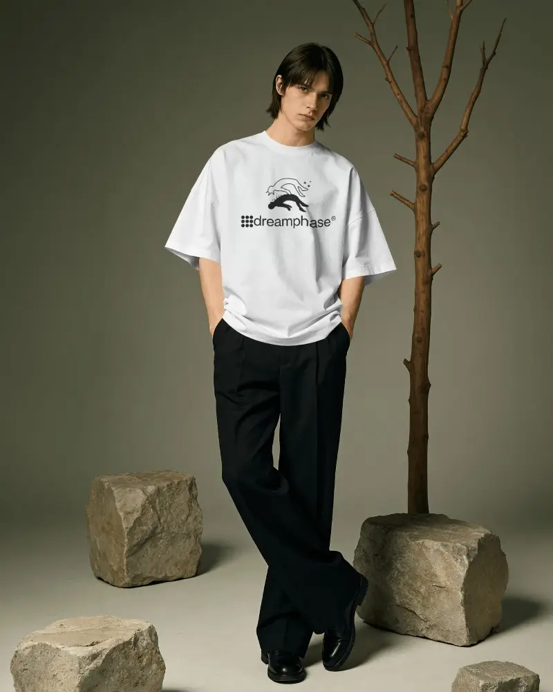 Organic Studio T Shirt Mockup Male Model Standing Beside Bare Tree And Stone Blocks