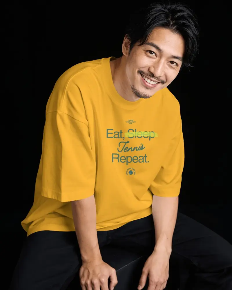 Seated T Shirt Mockup Male Model Smiling In Dark Studio With Relaxed Fashion Pose