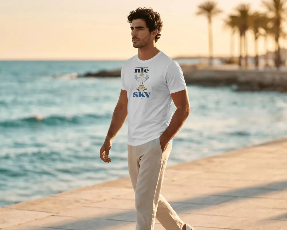 Coastal Sunset T Shirt Mockup Curly Haired Male Model Strolling Along The Seaside Boardwalk