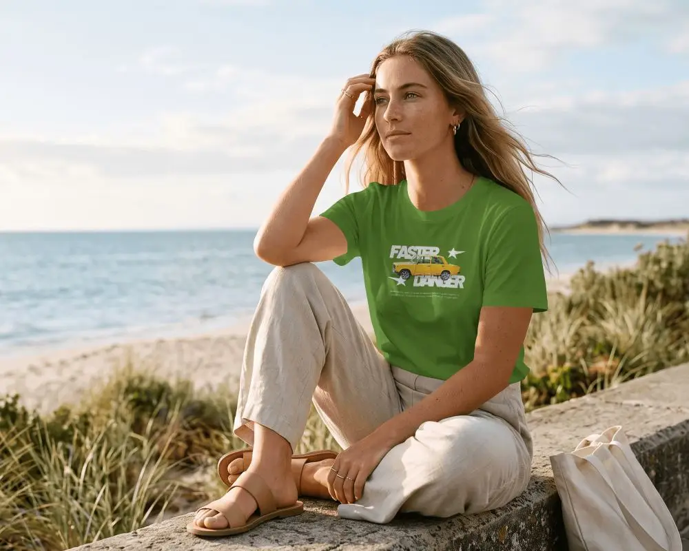 Coastal Lifestyle T Shirt Mockup Female Model Seated On Seawall With Windblown Hair And Trousers