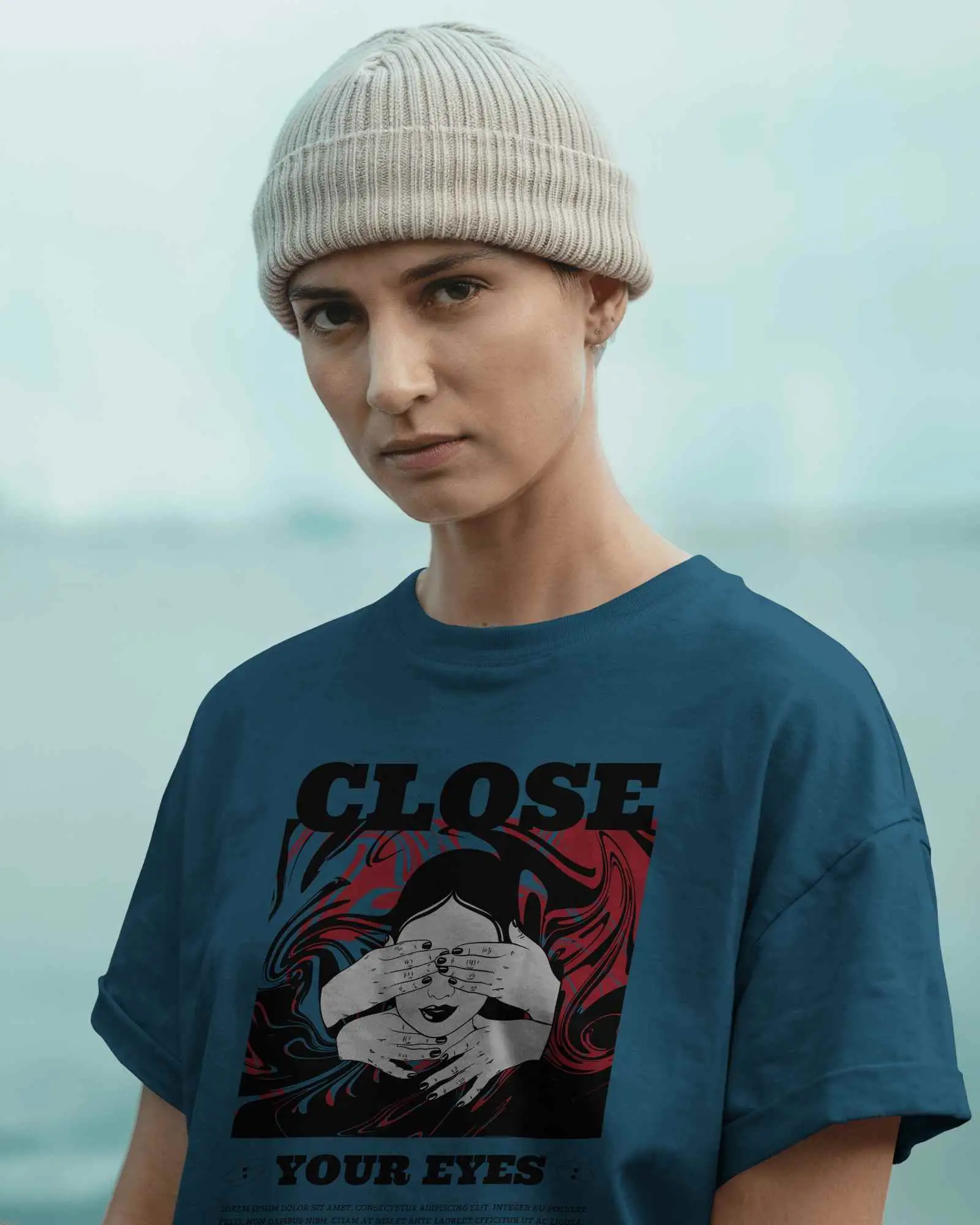 Outdoor Streetwear T Shirt Mockup Female Model Wearing Grey Tee And Beanie Staring Seriously With Light Blue Background