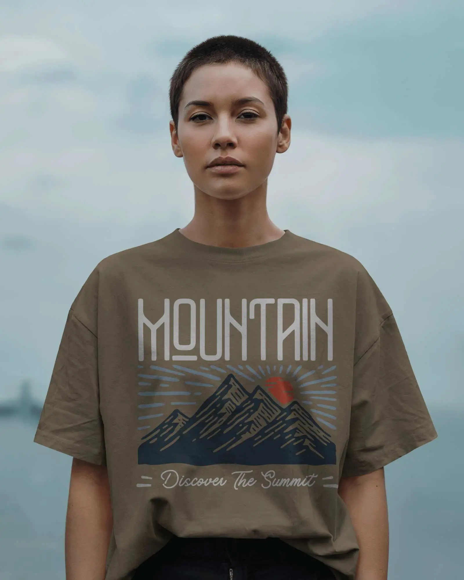 Outdoor T Shirt Mockup Female Model With Buzzcut In Grey Tee Facing Forward Under Cloudy Sky Minimalist Style