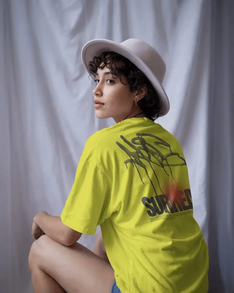 Studio Lit T Shirt Mockup Back View Female Model In White Hat Soft Curtain Background Elegant Pose