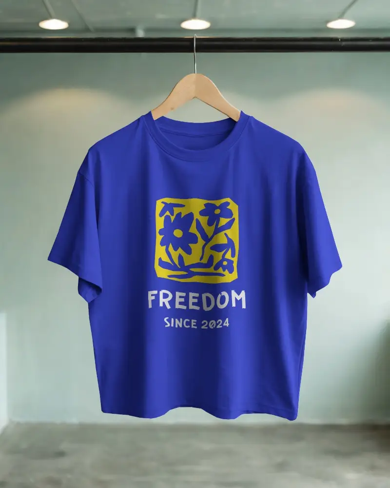 Industrial Styled Tshirt Mockup Hanging On Wooden Hanger With Soft Ceiling Lighting And Muted Concrete Floor Background