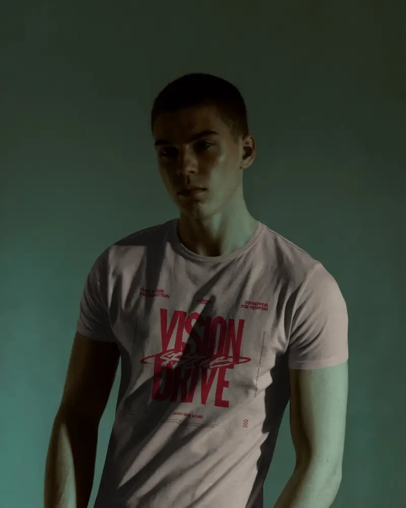 Moody Studio T Shirt Mockup Male Model In Shadowy Lighting With Modern Bold Graphic Design