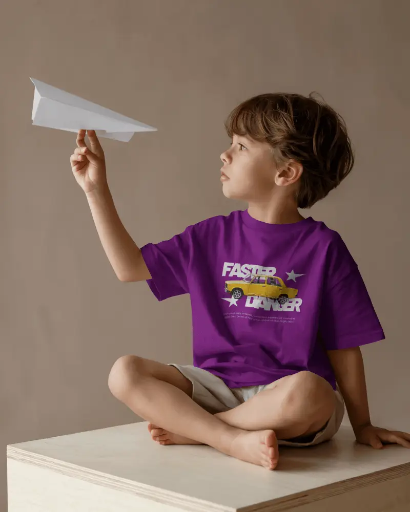 Kid Playing Paper Plane T Shirt Mockup Child Sitting On Wooden Box In Natural Light Setting