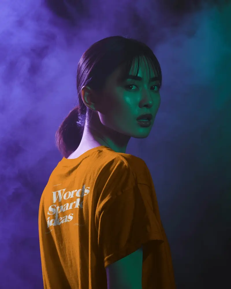 Neon Mist T Shirt Mockup Female Model In Studio With Purple And Green Smoky Light Effects