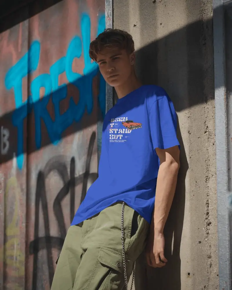 Urban Street Style T Shirt Mockup Worn By Young Man Leaning Against Rough Wall Background
