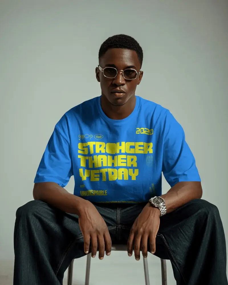 Front View Male T Shirt Mockup Model Seated On Stool With Confident Pose And Soft Studio