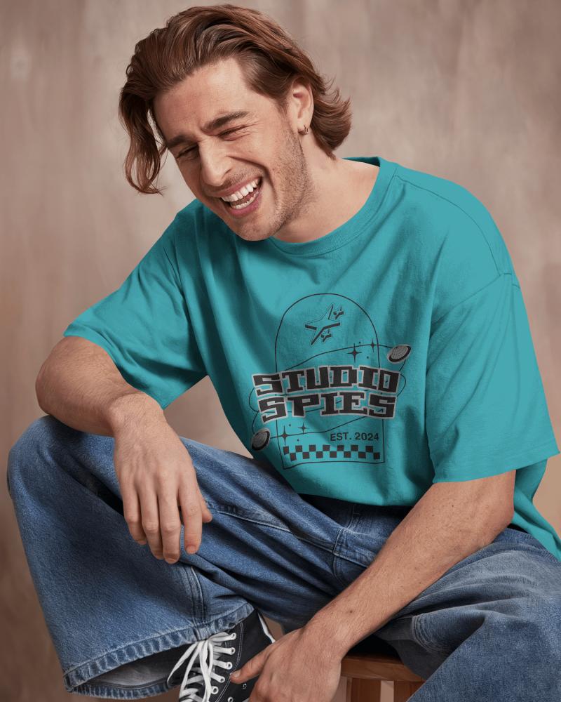 Studio Portrait Blank White Tshirt Mockup Smiling Male Model Sitting Casually In Loose Denim Soft Lighting Warm Backdrop Relaxed And Joyful Vibe 0893