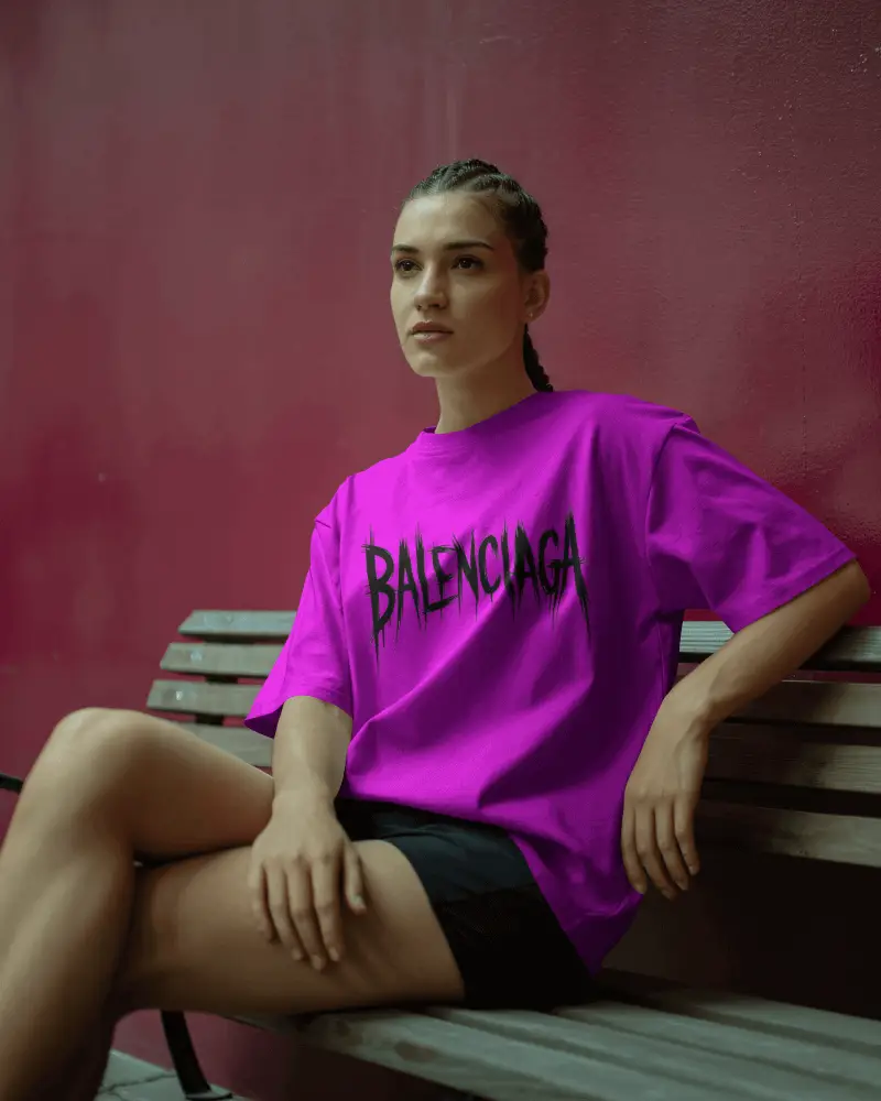 Relaxed Fit T Shirt Mockup Female Model Sitting On Bench With Bold Textured Wall Backdrop