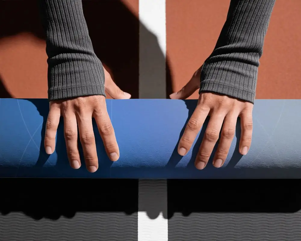 Close Up Of Hands Unrolling Textured Yoga Mat On Outdoor Gym Floor For Workout Session