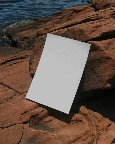 Blank Vertical Poster Mockup Leaning Against Natural Rock Surface Near Water Body