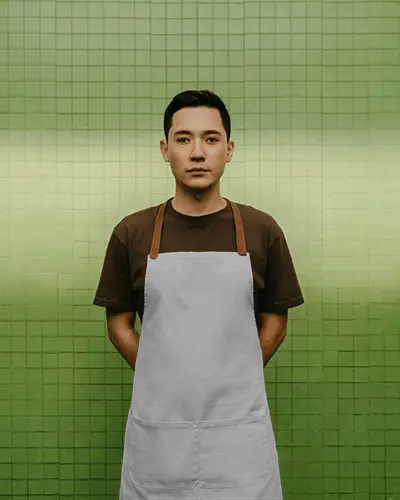 Front Facing Apron Mockup On Male Model Standing Against Tiled Wall Clean Uniform And Balanced Pose