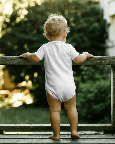 Outdoor Balcony Baby Onesie Mockup Back View Toddler Standing On Deck With Natural Scenic Depth