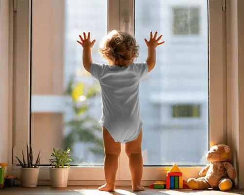 Sunlit Window Baby Onesie Mockup Back View Toddler Reaching Glass With Home Nursery Depth