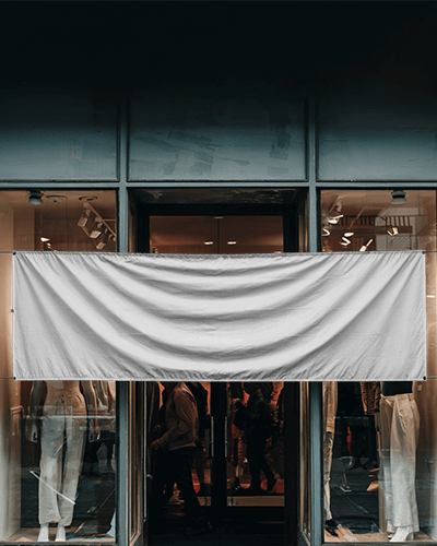 Fashion Boutique Outdoor Banner Mockup Hanging Over Storefront With Modern Window Display And Street Reflections