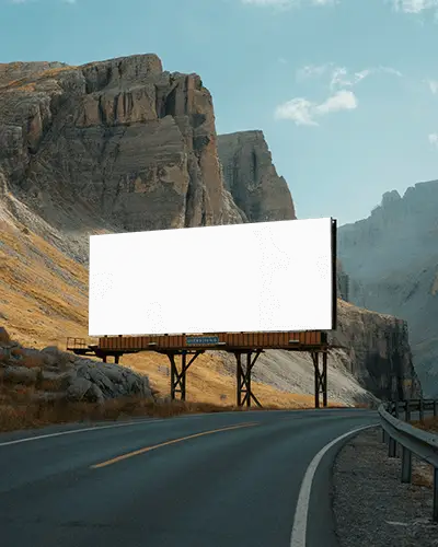 Empty Advertisement Billboard Mockup Standing On Desolate Road Surrounded By Rocky Mountain