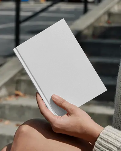 Outdoor Hand Holding Book Mockup On Steps In Soft Sunlight With Autumn Leaves