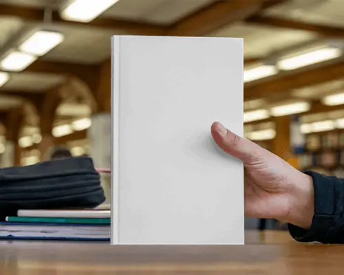 Hand Holding Book Mockup In Library With Books And Lights In Soft Depth Background