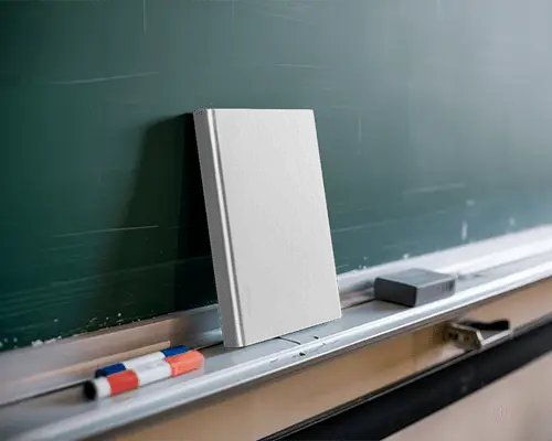 Leaning Book Mockup Against Board Tray With Markers And Eraser In Classroom Setting