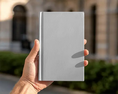 Hand Holding Blank Hardcover Book Mockup In Front Of Historic Building Outdoor Daylight Soft Shadows
