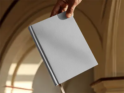 Person Holding Open Book Mockup By Corner Inside Arched Building Soft Sunlight On Minimal Backdrop