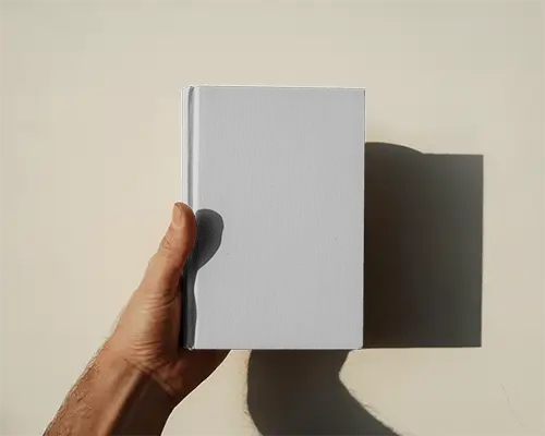 Book Cover Mockup Hand Holding Book Against Flat Light Wall With Long Casting Shadow