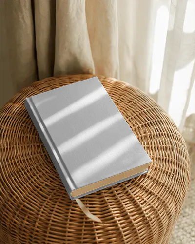 Hardcover Book Mockup Placed On Woven Surface With Curtain Light Stripes And Natural Textured Light