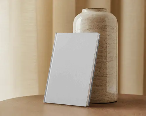 book-mockup-against-ceramic-vase-and-curtains-on-wooden-surface-soft-earthy-lighting