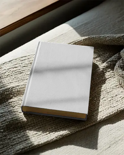 book-mockup-showcasing-plain-cover-resting-on-knit-blanket-in-warm-ambient-light
