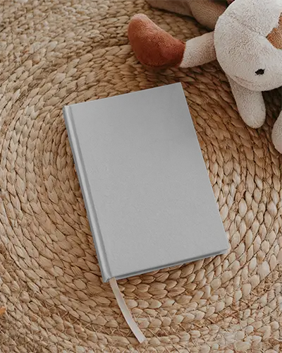 realistic-book-mockup-laying-on-handmade-rug-next-to-soft-toy-for-kid-friendly-projects