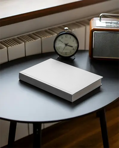 closed-hardback-book-mockup-displayed-on-desk-next-to-vintage-clock-radio