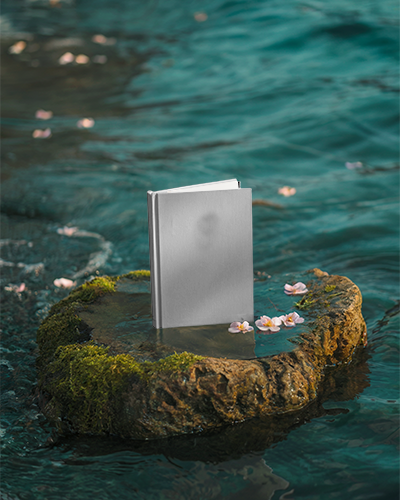 Hardcover Book Mockup Standing On Mossy Rock Surrounded By Calm Water With Delicate Flowers