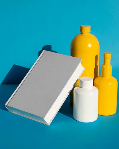 Hardcover Book Mockup Floating Among Cylindrical Bottles On Bright Surface Background