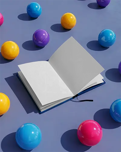 Open Book Mockup On Flat Surface Surrounded By Colorful Spherical Objects For Presentation