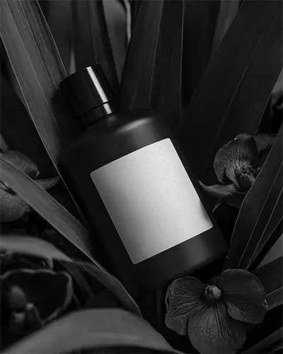 Sleek Cylindrical Bottle Mockup Surrounded By Organic Leaf And Floral Arrangement