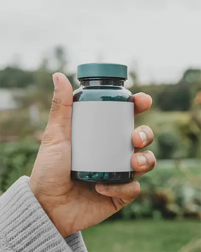 Hand Holding Clear Bottle Mockup With Black Label Capsule Supplement Container Mockup Outdoor