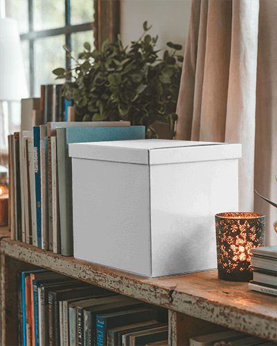Cozy Reading Nook Storage Box Mockup White Cardboard Box On Rustic Bookshelf With Warm Candlelight And Greenery 0121