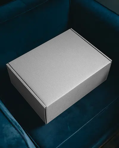 Minimal Cardboard Box Mockup On Navy Blue Sofa With Stylish Lighting For Modern Packaging