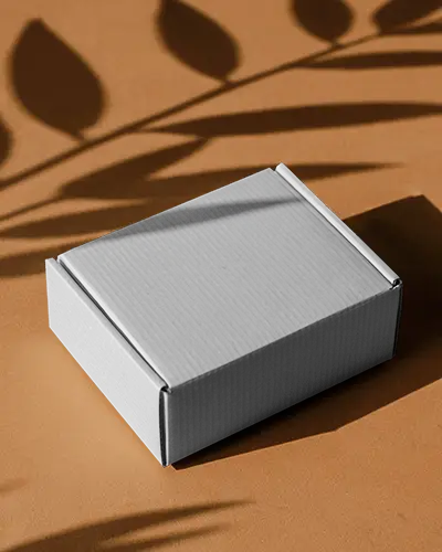 Cardboard Box Mockup On Brown Surface With Leaf Shadows For Organic And Minimal Packaging