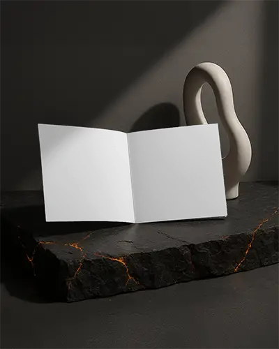 Open Square Brochure Mockup Placed On Dark Volcanic Textured Surface With Sculptural Background Soft Angled Lighting Premium Modern Promotional Display Scene
