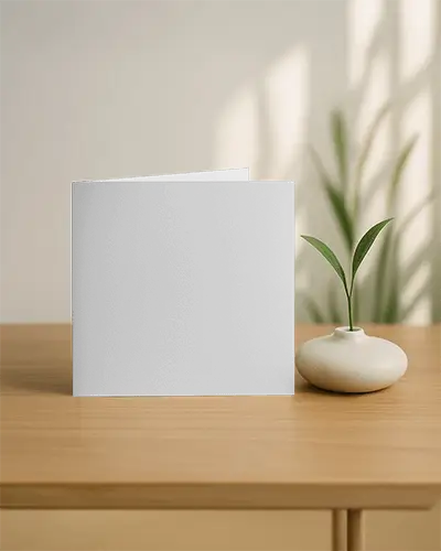 Square Folded Brochure Mockup Standing On Wooden Surface With Ceramic Vase And Soft Wall Lighting Cozy Modern Interior Minimal Promotional Display Scene
