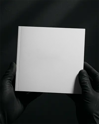 Square Brochure Mockup Held In Black Gloves Against Dark Background Featuring Promotion Vibrant And Bold Layout