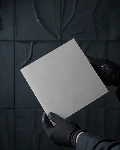 Square Brochure Mockup Hand Holding Promotional Leaflet In Front Of Dark Wall Background For Plumbing Services Branding